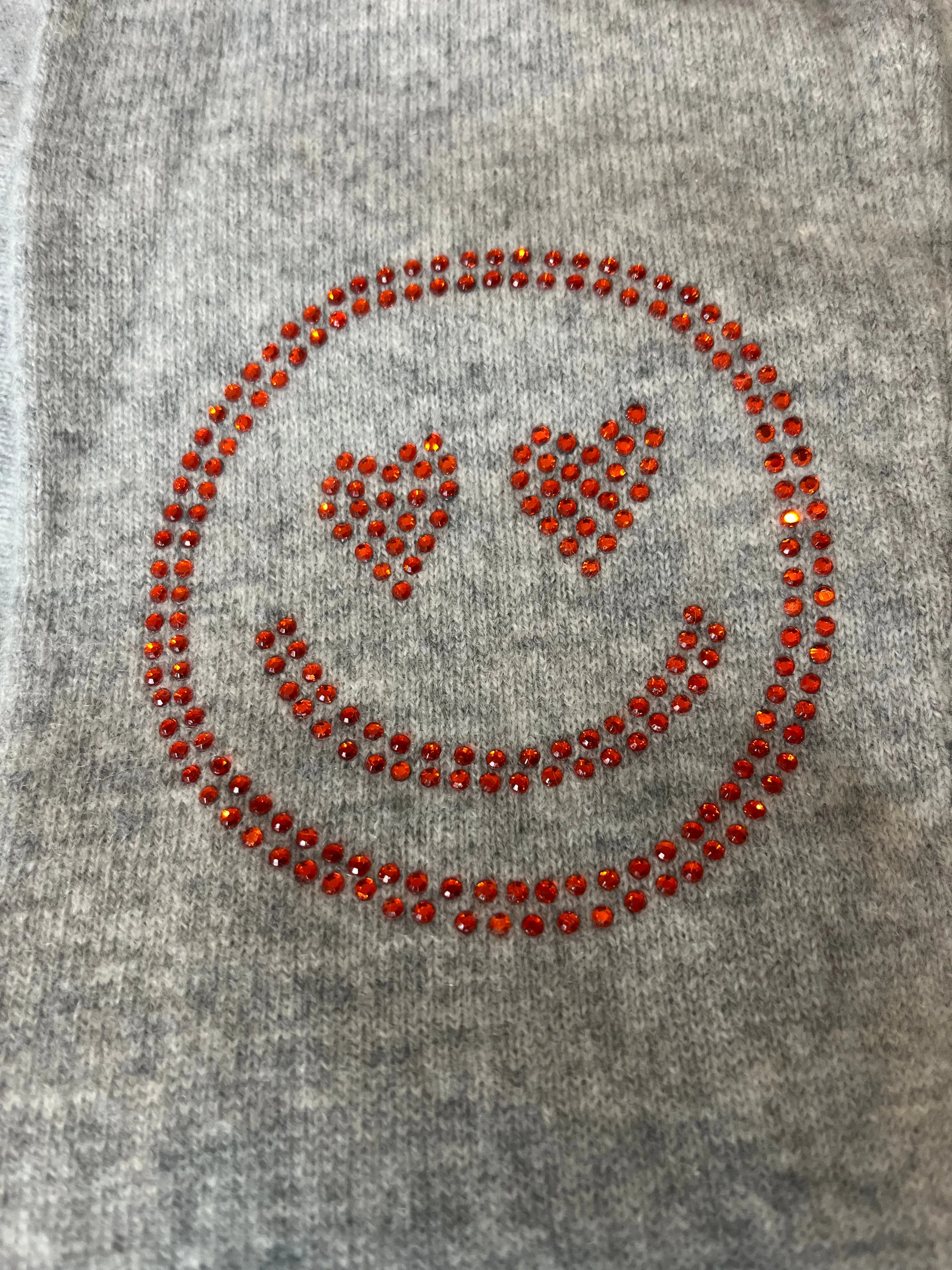 Grey cashmere plain knit beanie with an orange smiley embellishment & faux fur pom